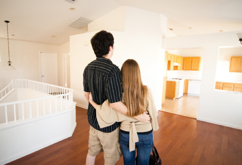 A couple looking at laptop in a living room of new house on moving day